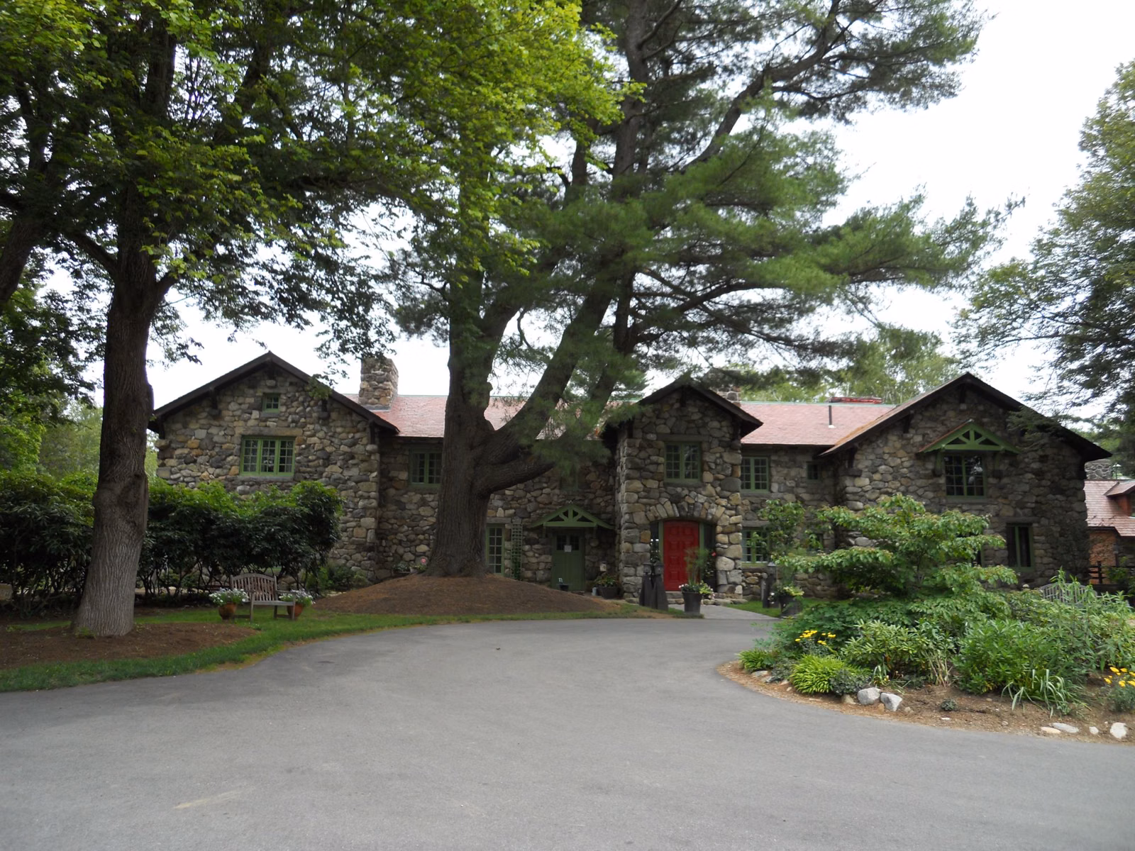 The stone Bradley Palmer house behind lawn and tall pines at Bradley Palmer State Park